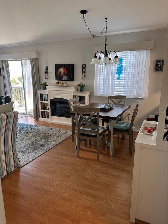 610 Ocean Marina Dr Unit 106, Flagler Beach, FL 32136 - dining area featuring wood finished floors, a glass covered fireplace, and a notable chandelier