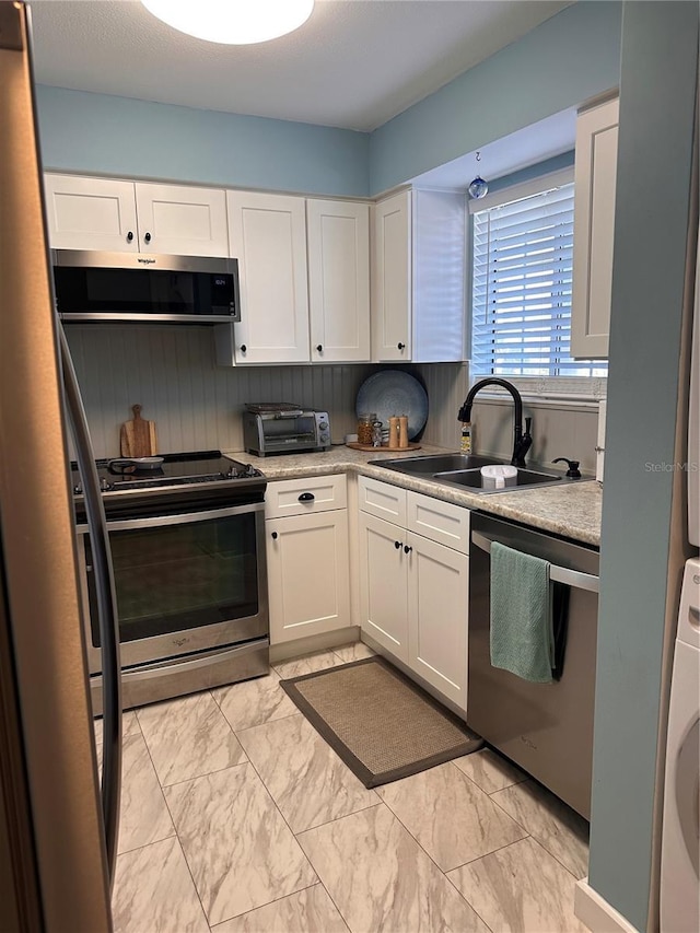 610 Ocean Marina Dr Unit 106, Flagler Beach, FL 32136 - kitchen featuring white cabinets, marble finish floor, washer / clothes dryer, stainless steel appliances, and a sink
