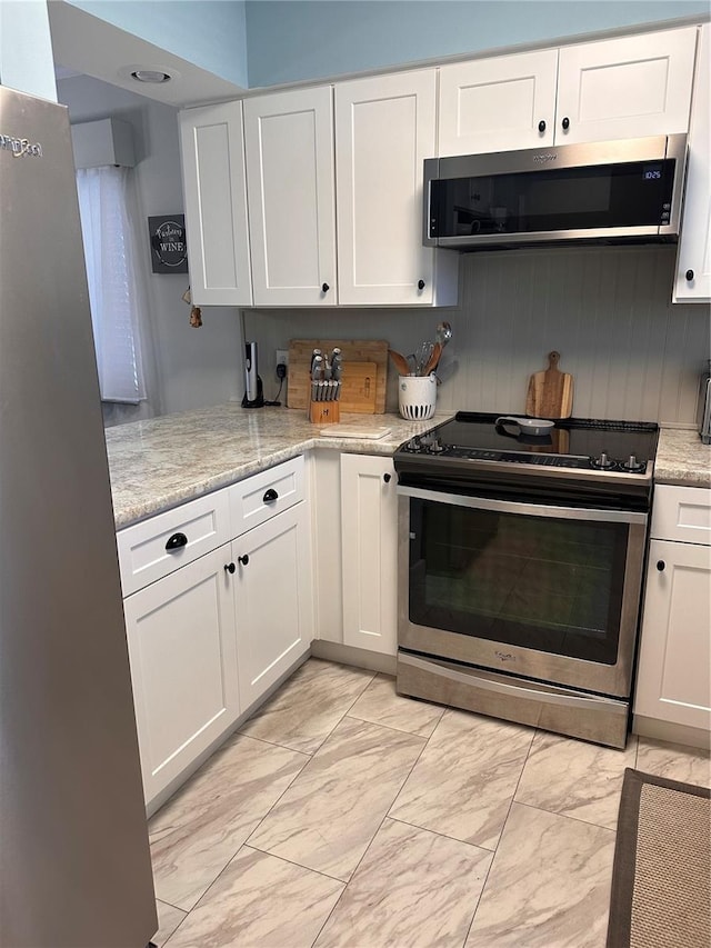 kitchen featuring light stone counters, appliances with stainless steel finishes, and white cabinetry