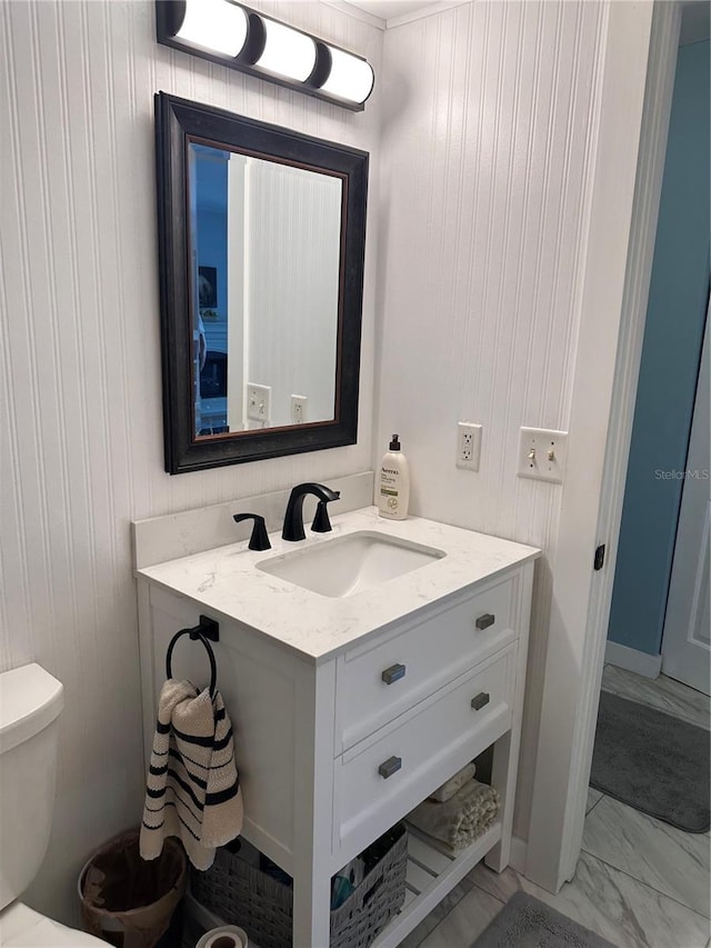 bathroom featuring wooden walls, vanity, and toilet