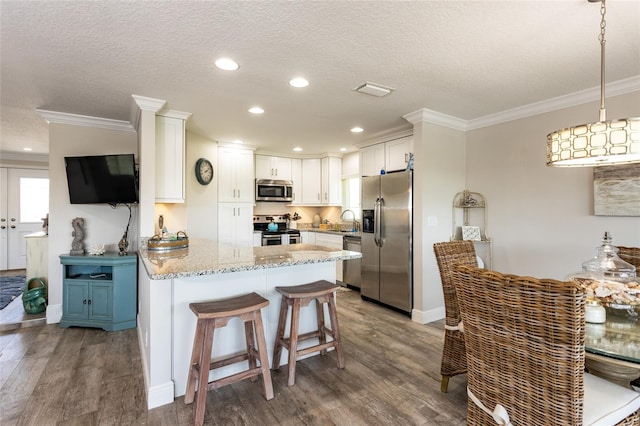 kitchen featuring white cabinets, dark hardwood / wood-style flooring, pendant lighting, stainless steel appliances, and sink