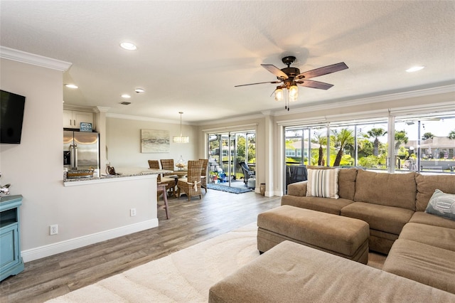 living room featuring light hardwood / wood-style flooring, a textured ceiling, ceiling fan, and crown molding