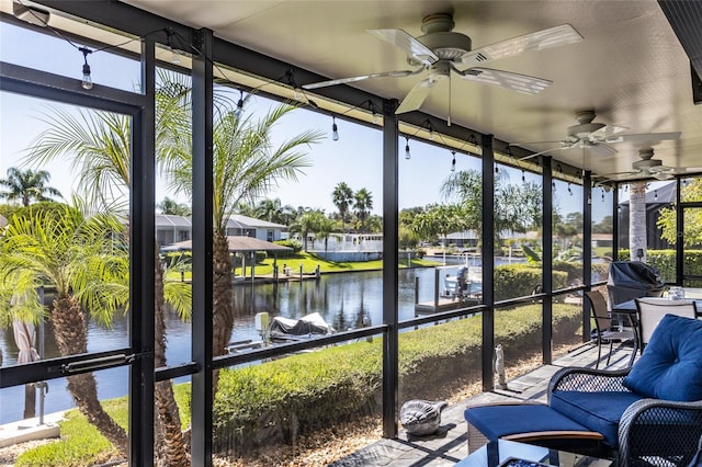 sunroom featuring a water view and ceiling fan