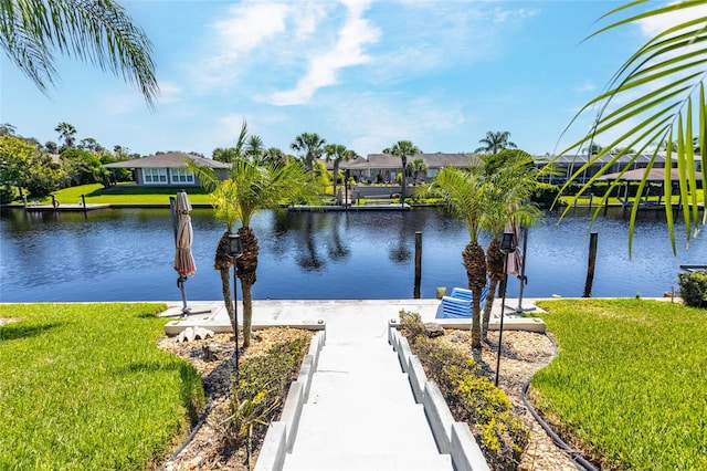 view of dock featuring a lawn and a water view