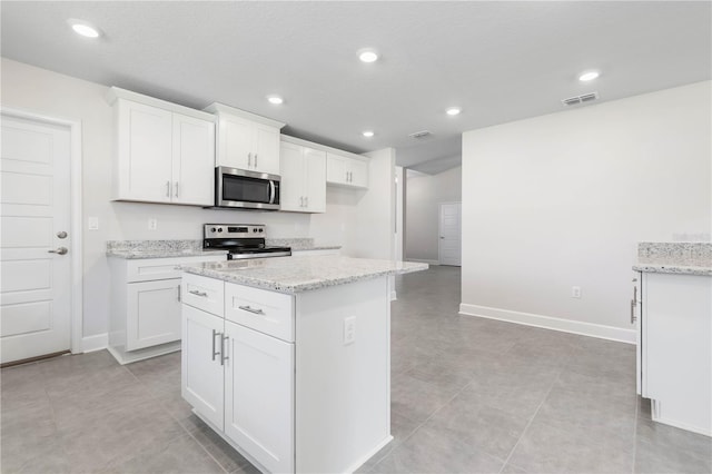 kitchen featuring light stone counters, a kitchen island, a textured ceiling, white cabinetry, and stainless steel appliances