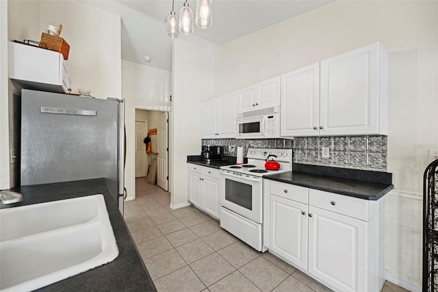 kitchen with white appliances, sink, hanging light fixtures, white cabinets, and light tile patterned floors