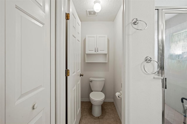 bathroom with tile patterned floors, a shower with shower door, a textured ceiling, and toilet