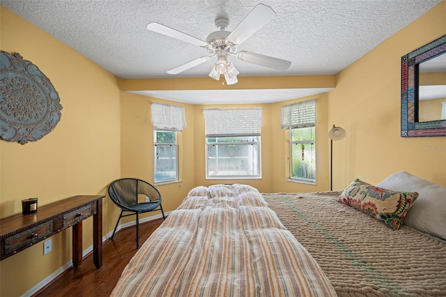 bedroom featuring dark hardwood / wood-style flooring, a textured ceiling, and ceiling fan