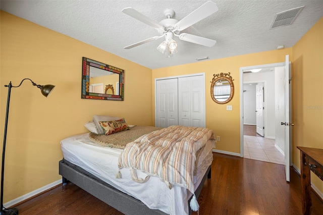 bedroom featuring a closet, a textured ceiling, wood-type flooring, and ceiling fan