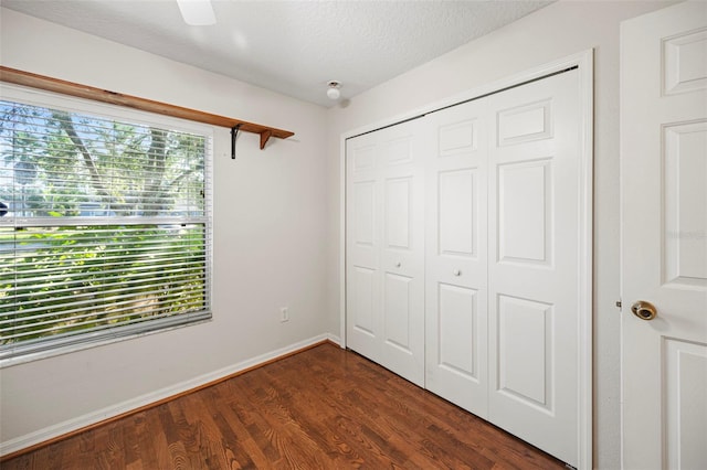 unfurnished bedroom featuring a textured ceiling, dark hardwood / wood-style floors, a closet, and ceiling fan