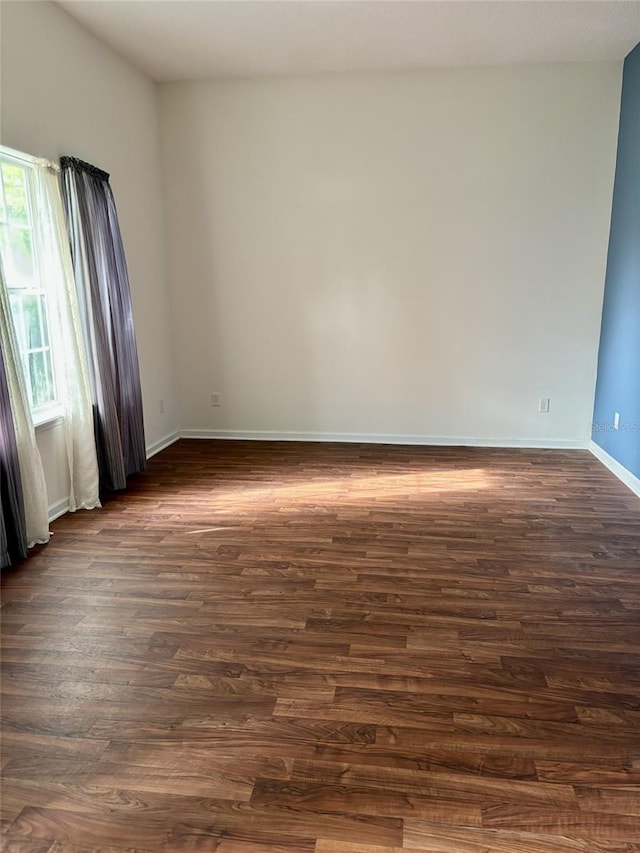 spare room with dark wood-style flooring and baseboards