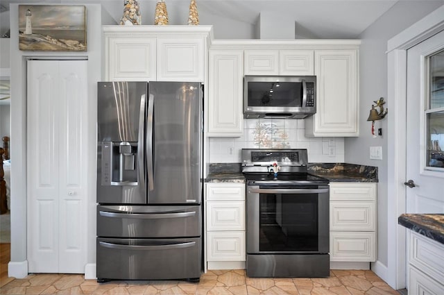 kitchen featuring appliances with stainless steel finishes, decorative backsplash, white cabinetry, and dark stone counters