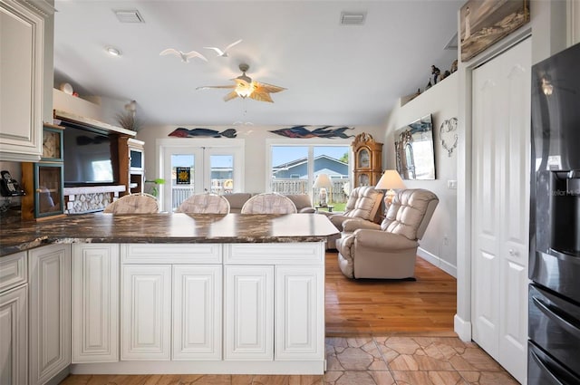 kitchen featuring ceiling fan, stainless steel fridge, kitchen peninsula, french doors, and light wood-type flooring