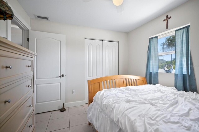 tiled bedroom featuring ceiling fan and a closet