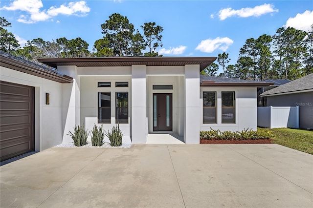 view of front of home featuring a garage, fence, and stucco siding