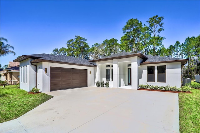 prairie-style home featuring a garage, driveway, a front yard, and stucco siding