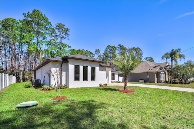 view of front of house featuring central AC unit, concrete driveway, fence, a front yard, and stucco siding