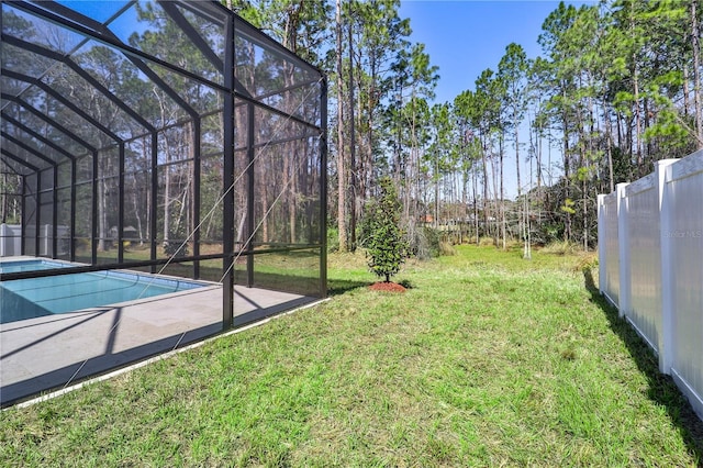 view of yard featuring a lanai, fence, and an outdoor pool