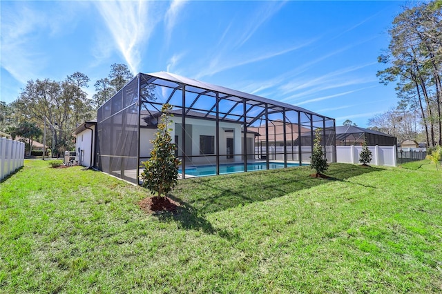 rear view of house featuring a lawn, fence, a fenced in pool, and a lanai