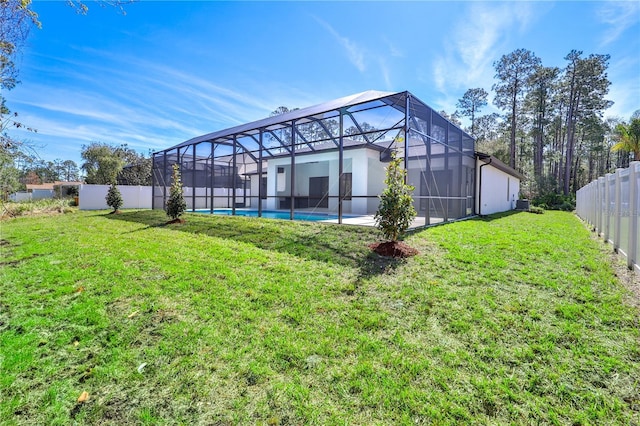 rear view of property with a fenced in pool, a lanai, a fenced backyard, and a lawn