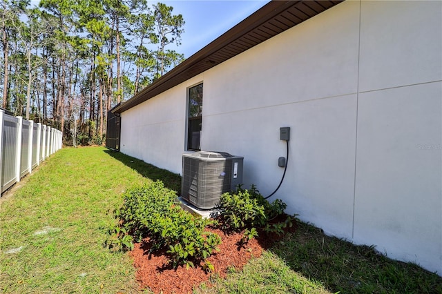 view of side of home featuring stucco siding, fence, cooling unit, and a yard