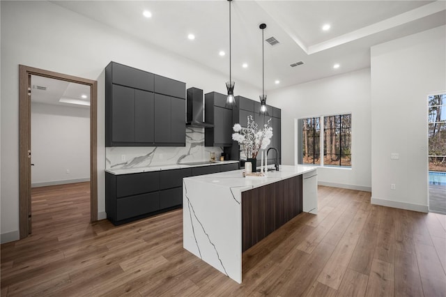 kitchen featuring light wood finished floors, tasteful backsplash, visible vents, an island with sink, and modern cabinets