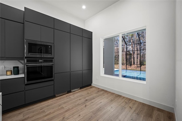 kitchen featuring black appliances, modern cabinets, baseboards, and light wood-style floors