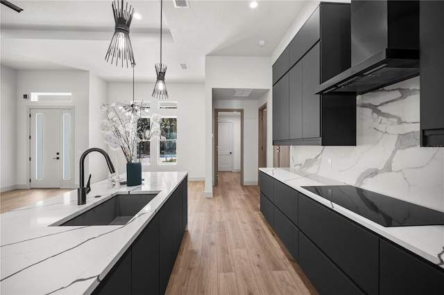 kitchen with wall chimney exhaust hood, modern cabinets, dark cabinets, black electric cooktop, and a sink