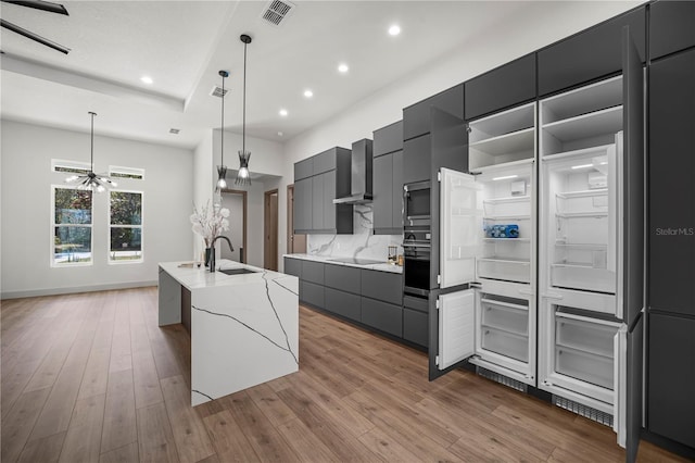 kitchen featuring wall chimney range hood, modern cabinets, visible vents, and gray cabinets