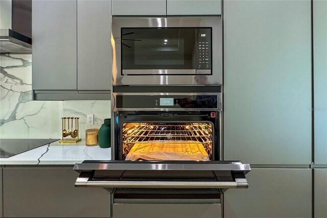 interior details featuring black appliances, tasteful backsplash, and wall chimney exhaust hood