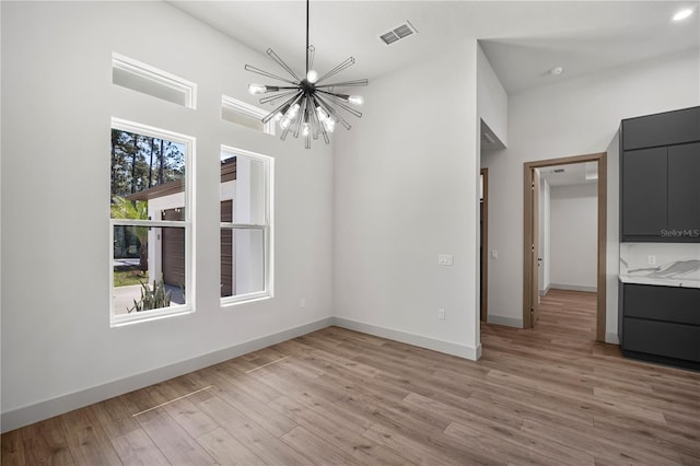 interior space with a chandelier, baseboards, visible vents, and light wood finished floors