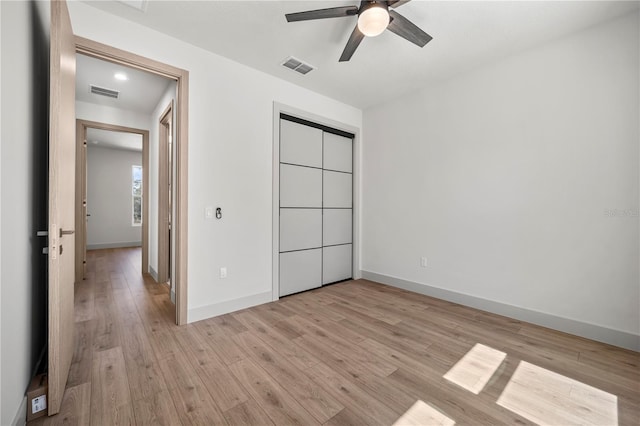 unfurnished bedroom featuring light wood-style floors, a closet, and visible vents