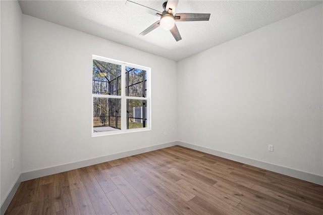 unfurnished room with a ceiling fan, a textured ceiling, baseboards, and wood finished floors