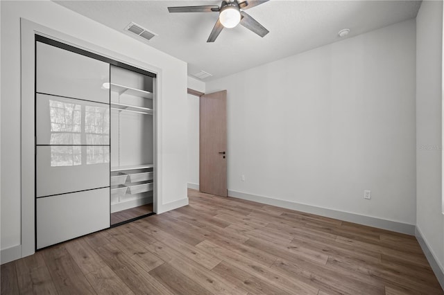 unfurnished bedroom with baseboards, visible vents, ceiling fan, wood finished floors, and a closet