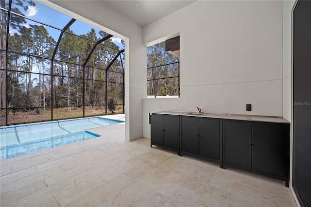 pool with a patio, a sink, and glass enclosure