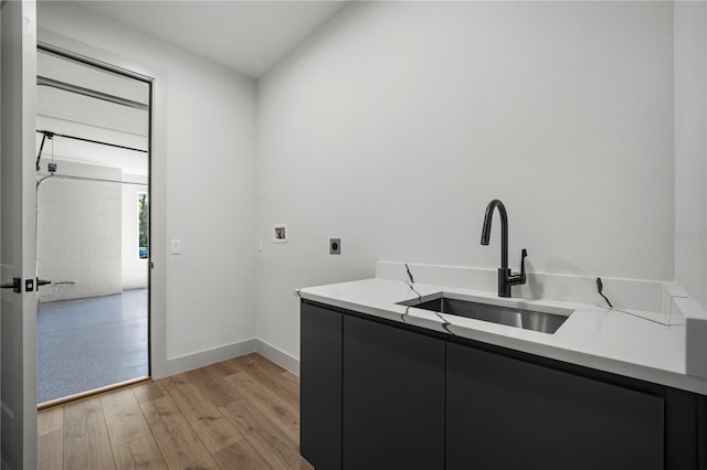 clothes washing area featuring hookup for an electric dryer, washer hookup, a sink, light wood-style floors, and cabinet space