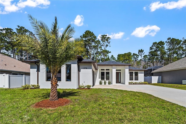 prairie-style house featuring fence, driveway, a front lawn, and stucco siding