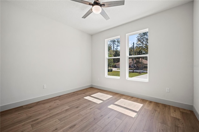 spare room featuring light wood-type flooring, ceiling fan, and baseboards