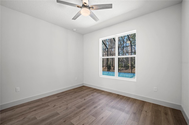 unfurnished room with a textured ceiling, wood finished floors, a ceiling fan, and baseboards