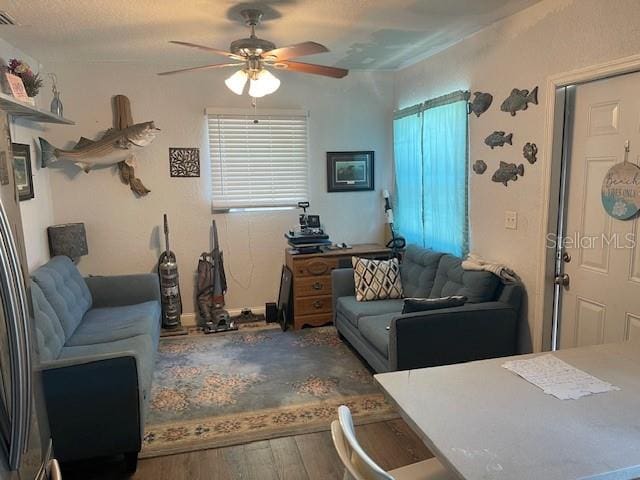 living room featuring a textured ceiling, wood-type flooring, and ceiling fan