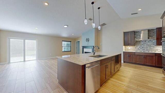 kitchen with lofted ceiling, sink, decorative light fixtures, wall chimney range hood, and dishwasher