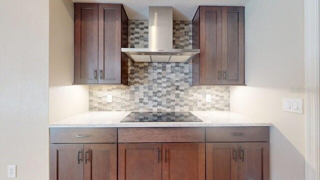 kitchen with wall chimney exhaust hood, backsplash, and black electric stovetop