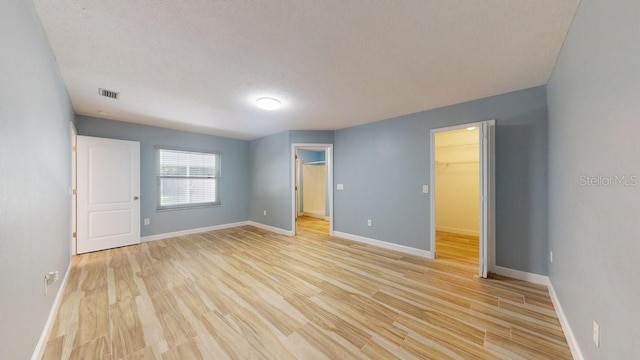 empty room with a textured ceiling and light hardwood / wood-style flooring