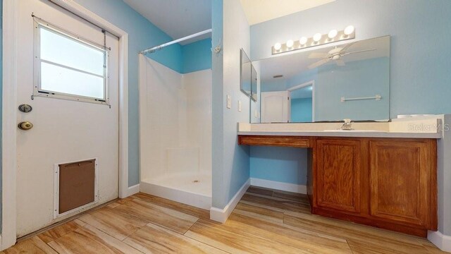 bathroom with a shower, vanity, ceiling fan, and wood-type flooring