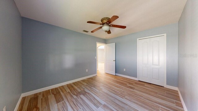 unfurnished bedroom with light hardwood / wood-style flooring, a closet, and ceiling fan