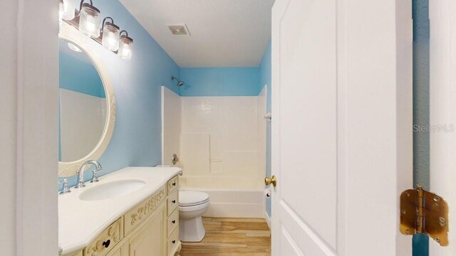 full bathroom featuring washtub / shower combination, hardwood / wood-style floors, toilet, and vanity