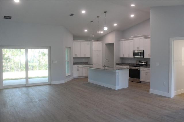 kitchen featuring white cabinets, appliances with stainless steel finishes, high vaulted ceiling, and a kitchen island with sink