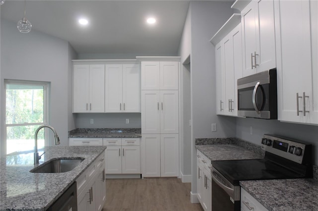 kitchen with appliances with stainless steel finishes, light stone counters, sink, light hardwood / wood-style floors, and white cabinetry