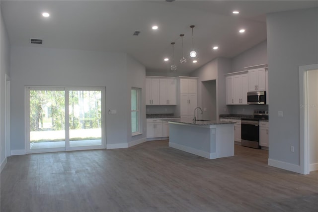 kitchen featuring high vaulted ceiling, an island with sink, decorative light fixtures, white cabinetry, and stainless steel appliances