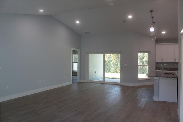 unfurnished living room with dark hardwood / wood-style floors, high vaulted ceiling, and sink